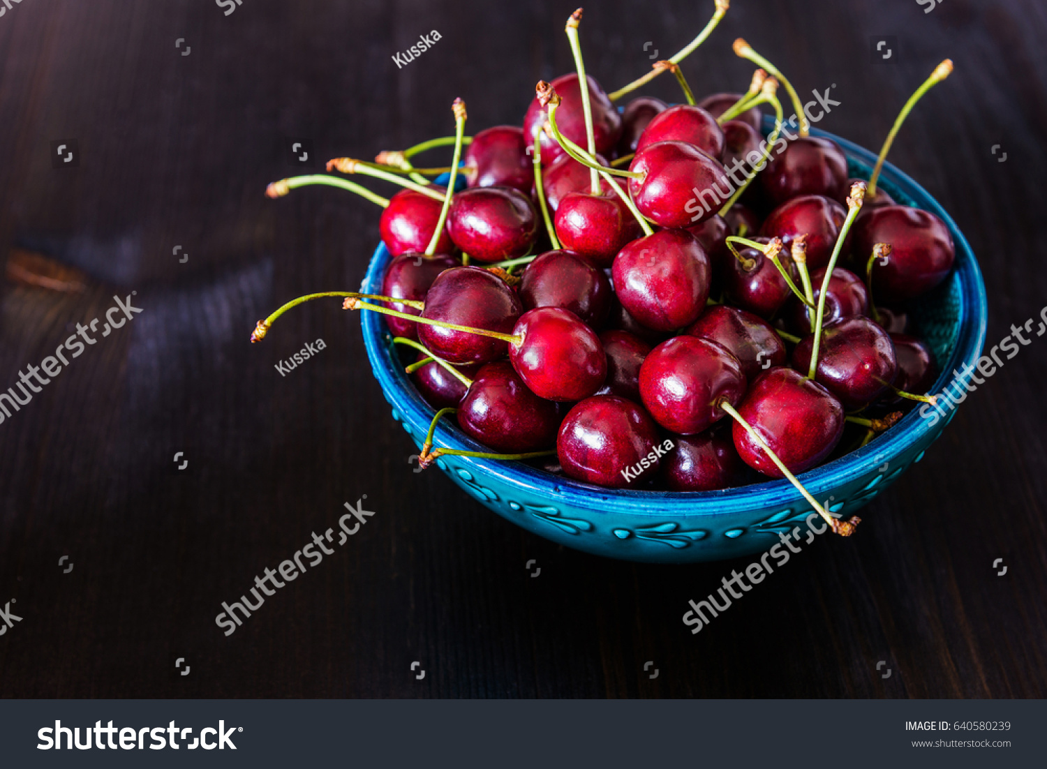 red cherries in green ceramic bowl on dark background
 #640580239