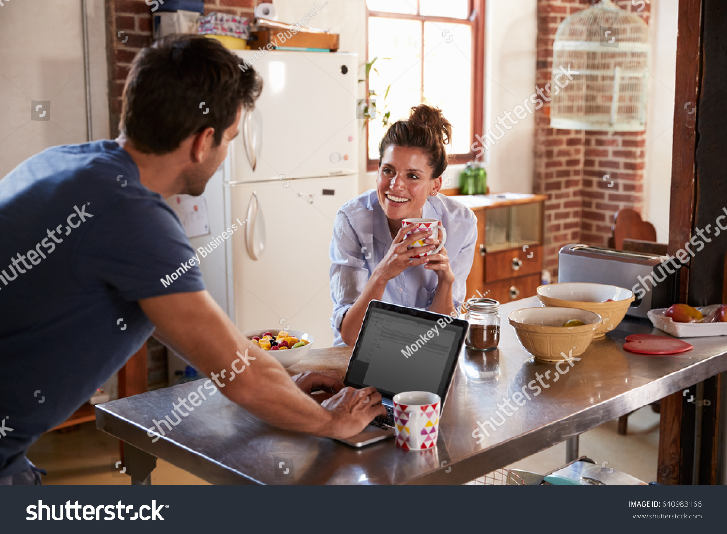 Happy Hispanic couple using computer in kitchen, waist up #640983166