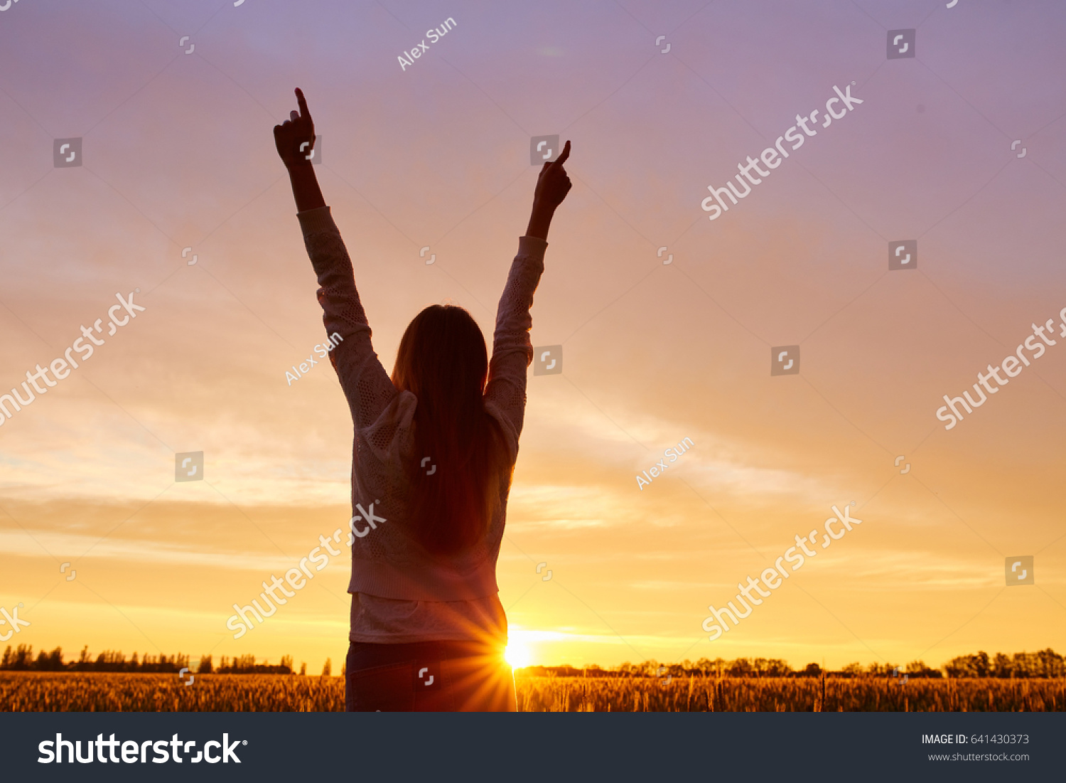 Girl with open arms on a green wheat field in the morning #641430373