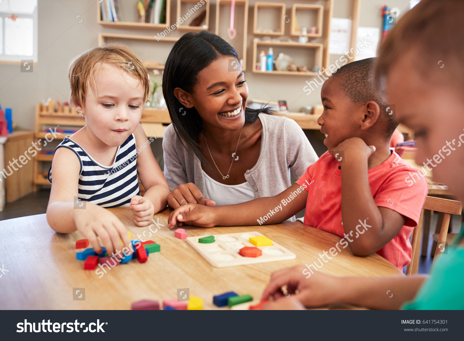 Teacher And Pupils Using Wooden Shapes In Montessori School #641754301