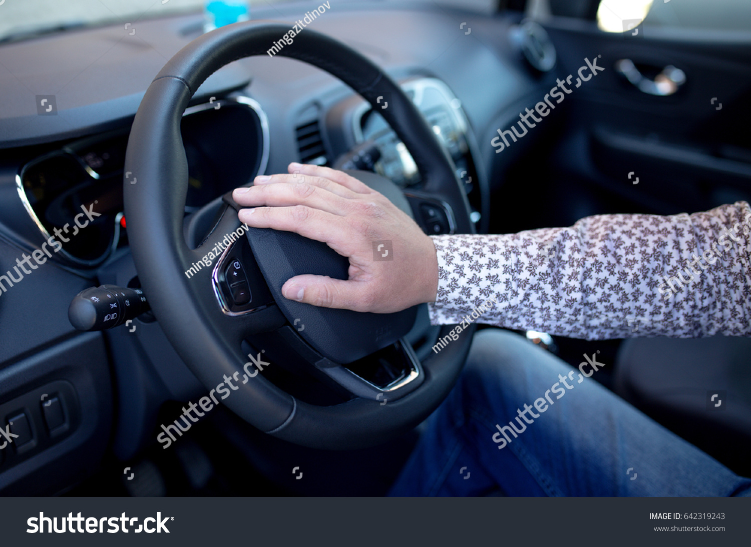 The person controls the steering wheel and presses the horn while driving. Hand on the dashboard in a car #642319243
