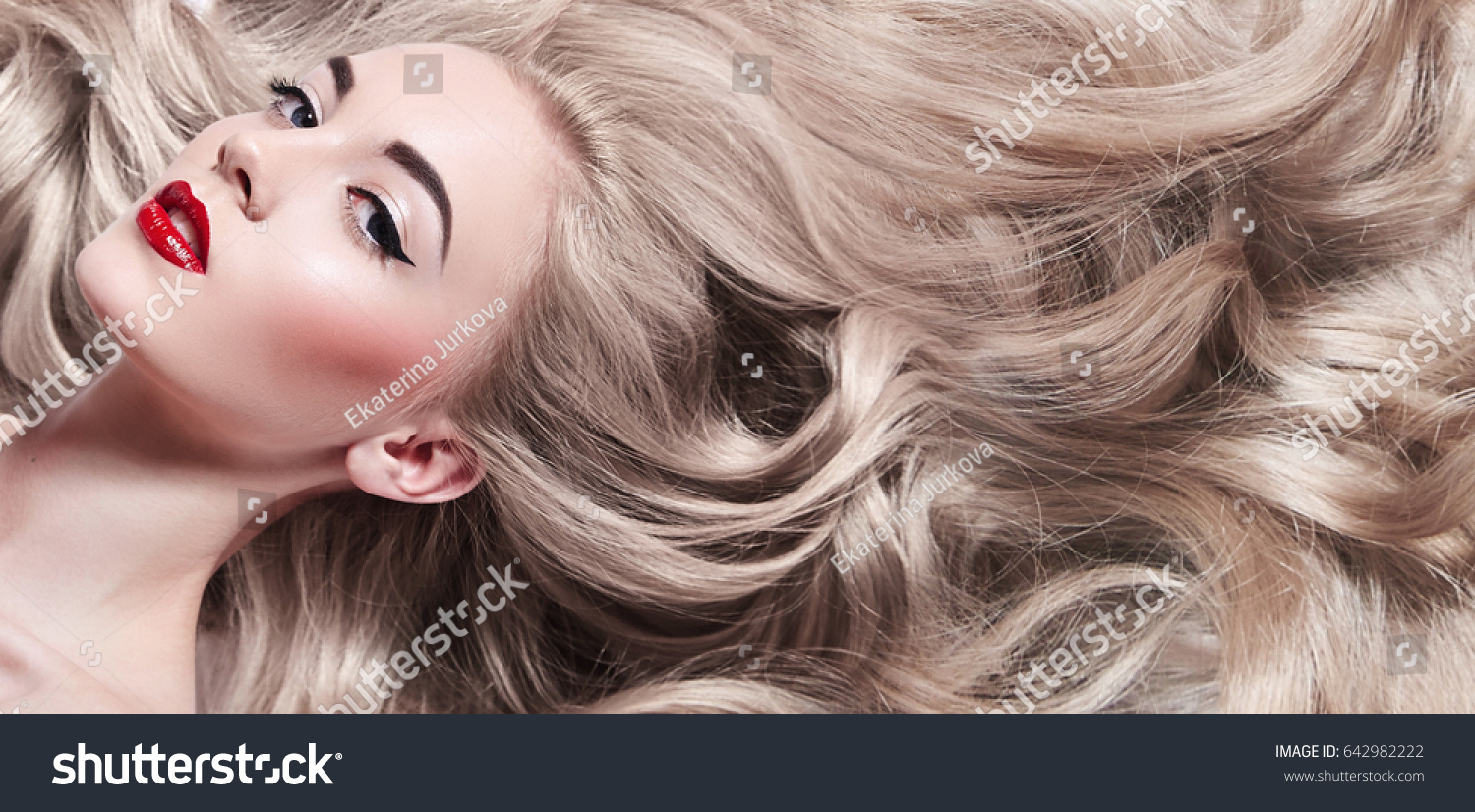 Beautiful young well-groomed girl lies - close-up. Long light shiny healthy well-groomed long hair. Advertising of hair care, cosmetics, beauty. Makeup - red lips, black arrows, mascara. #642982222