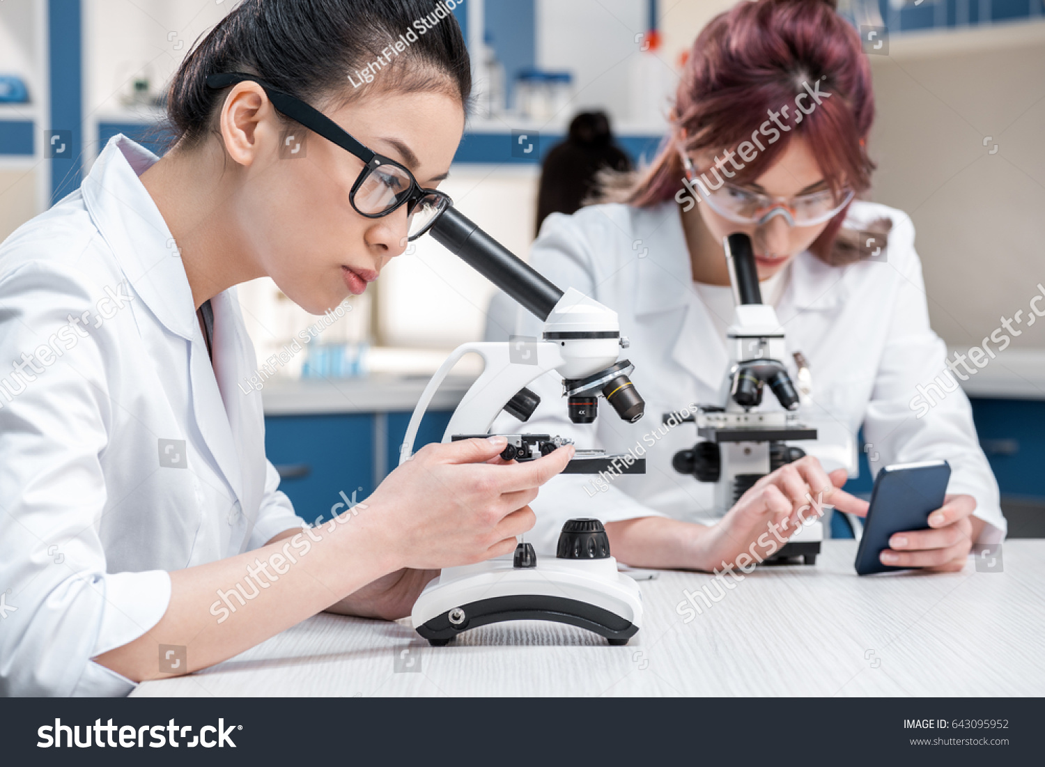 scientists group working with microscopes and smartphone in chemical lab, lab scientists concept #643095952