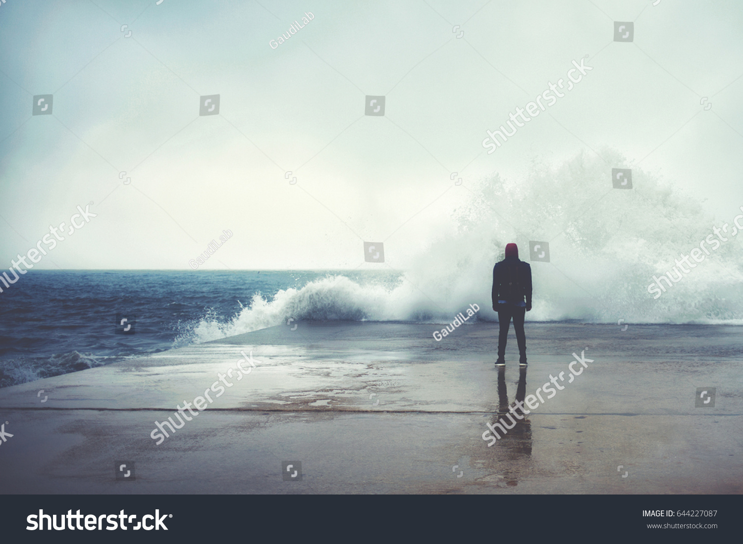 Feeling of freedom, back view of adult man standing on pier facing to the sea with big waves beats against the shore on a cloudy autumn day, alone depress person,the power of nature, storm on seashore #644227087