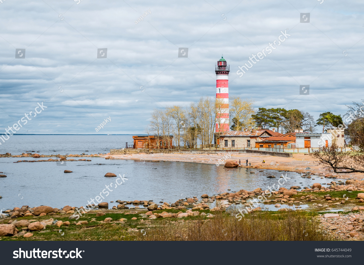 View of the cape on the coast with the old lighthouse in red and white stripes #645744049