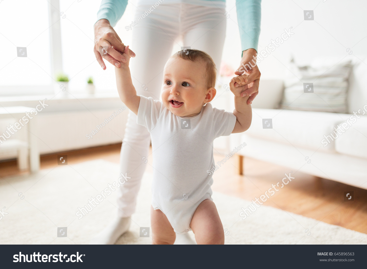 family, child, childhood and parenthood concept - happy little baby learning to walk with mother help at home #645896563