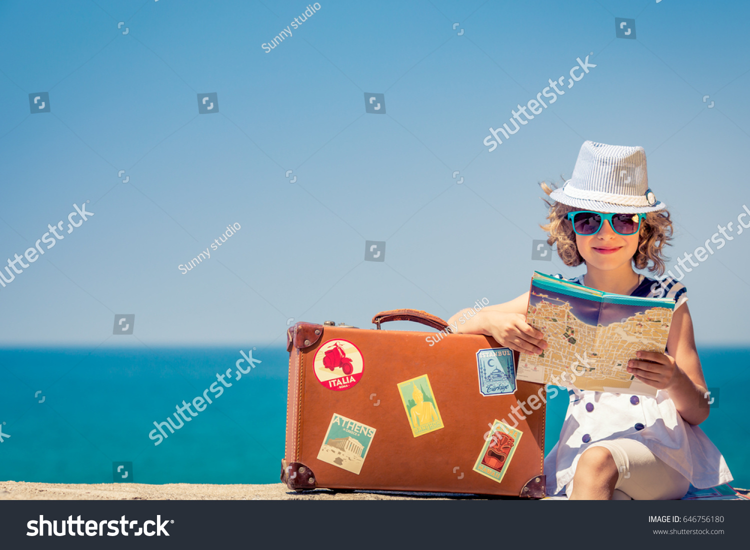 Happy child with vintage suitcase and city map. Kid having fun on summer vacation. Travel and adventure concept #646756180