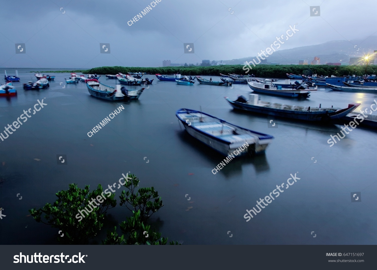 Morning scenery of Tamsui River with motor boats parking on the tranquil water and mangroves in the foreground under moody cloudy sky in Taipei Taiwan #647151697