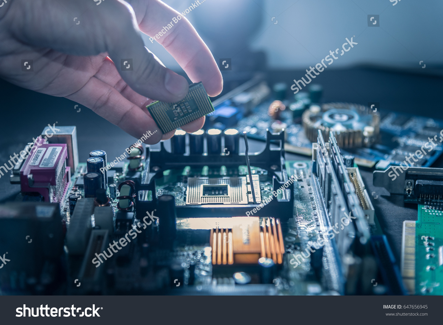 The technician is putting the CPU on the socket of the computer motherboard. #647656945