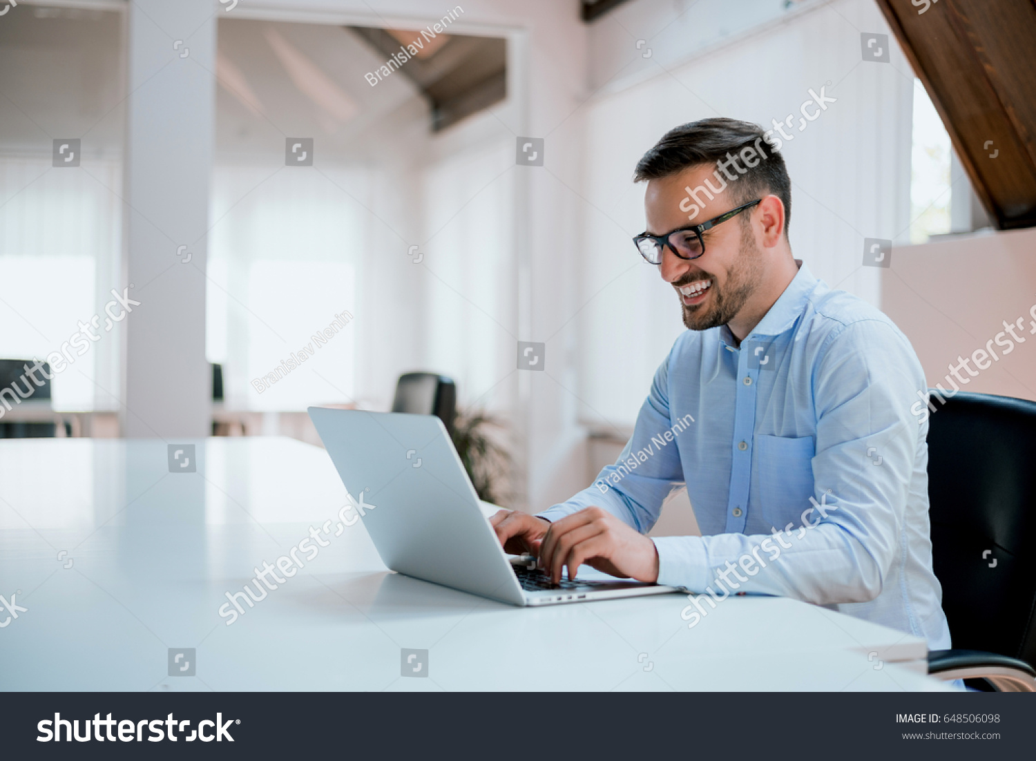Portrait of young man sitting at his desk in the office #648506098