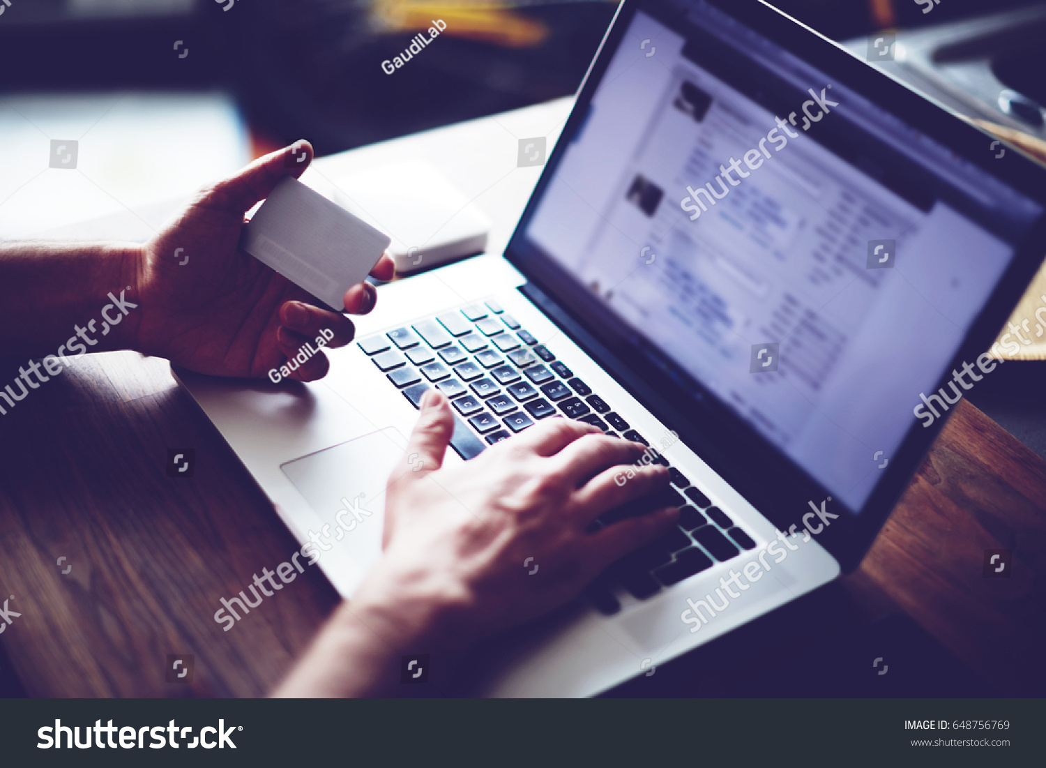 Cropped shot of a man's hands using a laptop at home while holding credit card in the hands, online shopping at home, cross process, filtered image #648756769