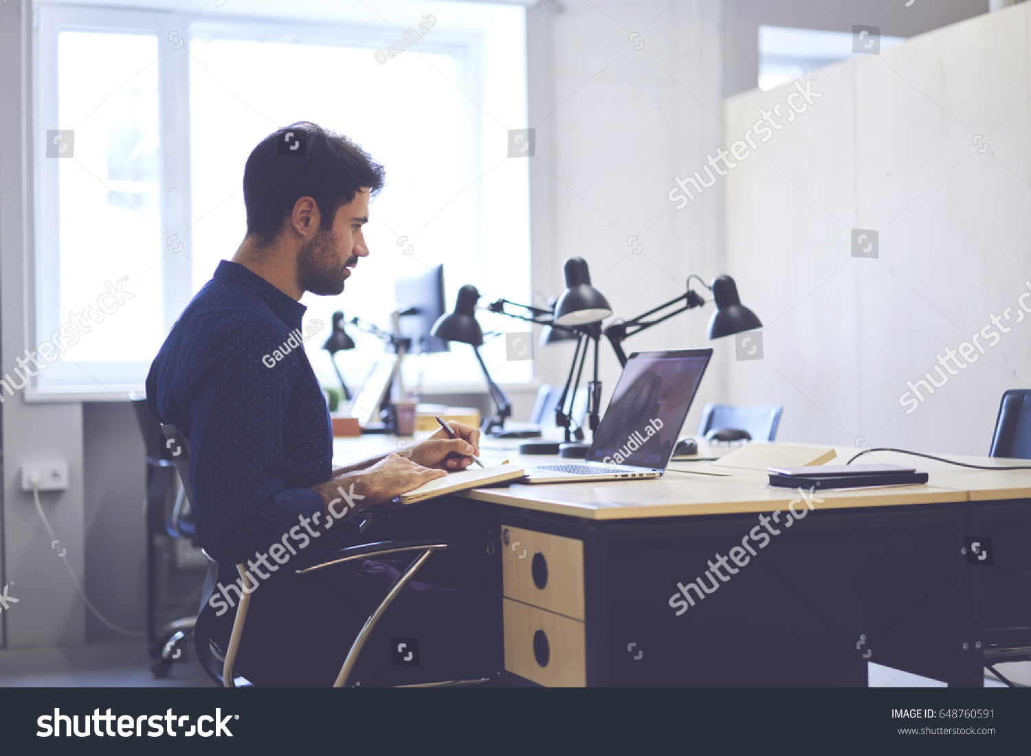 Concentrated male journalist browsing information from social networks preparing article noting ideas, professional handsome copywriter working on creation advertising content for marketing website   #648760591