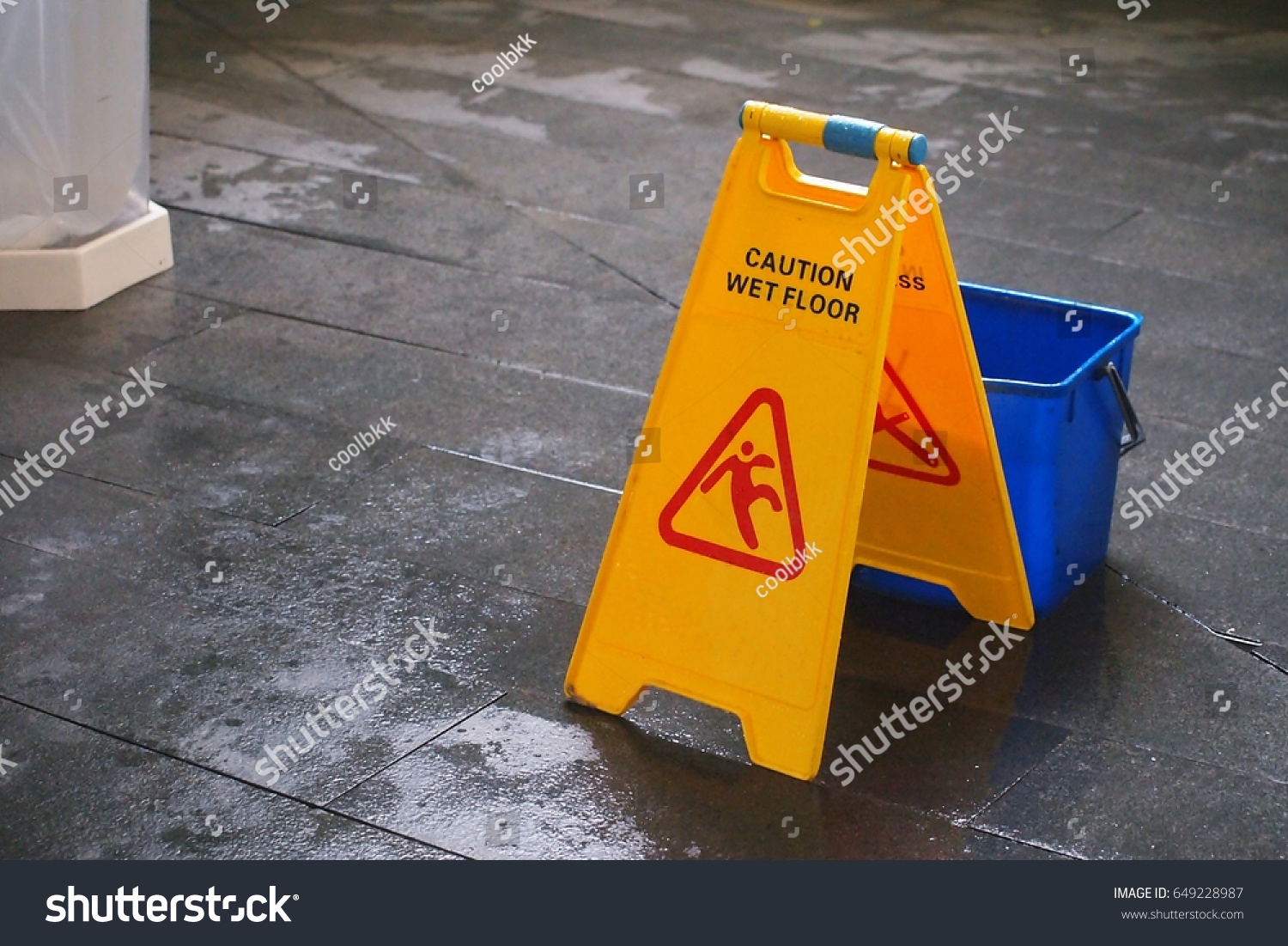 Yellow Caution wet floor sign on wet floor with blue bucket
 #649228987
