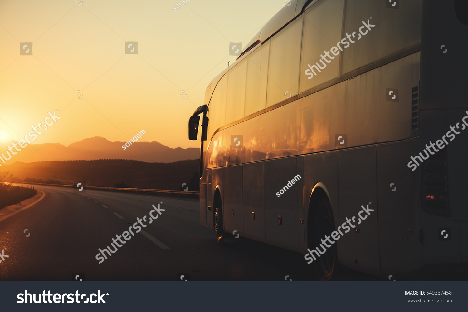 White bus driving on road towards the setting sun #649337458