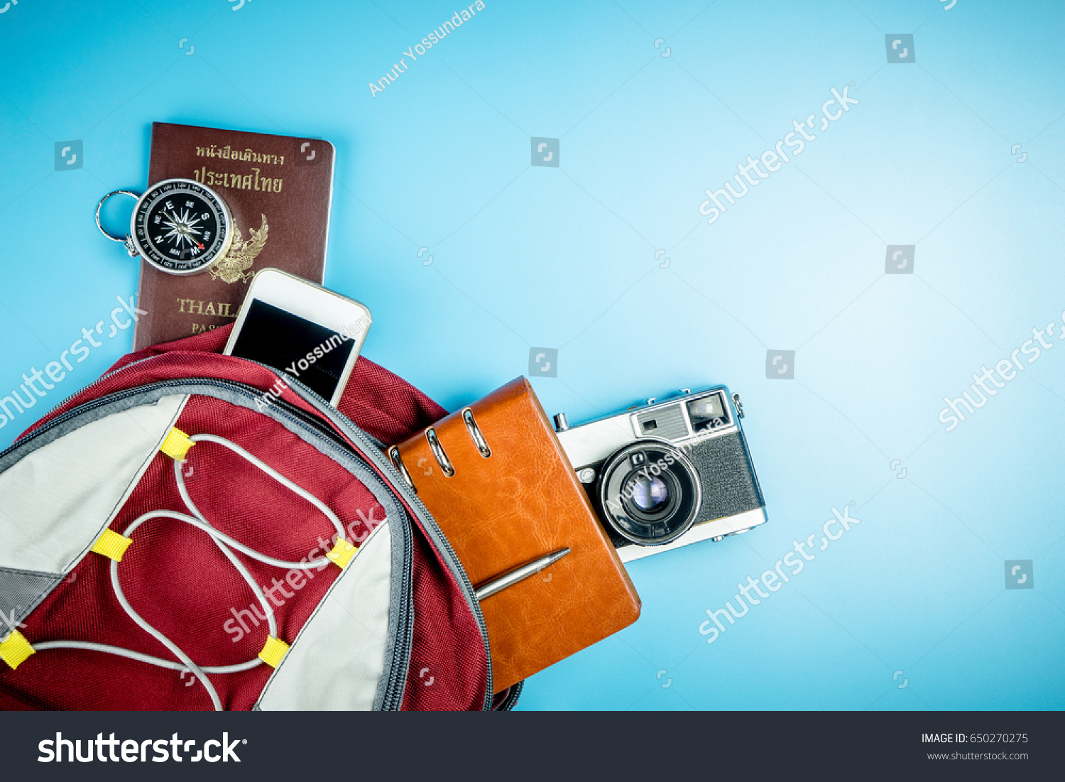 Traveler Backpack with travel accessories on blue copy space for Backpacker Vacation and Travel concept with camera passport mobile phone notebook and compass. #650270275