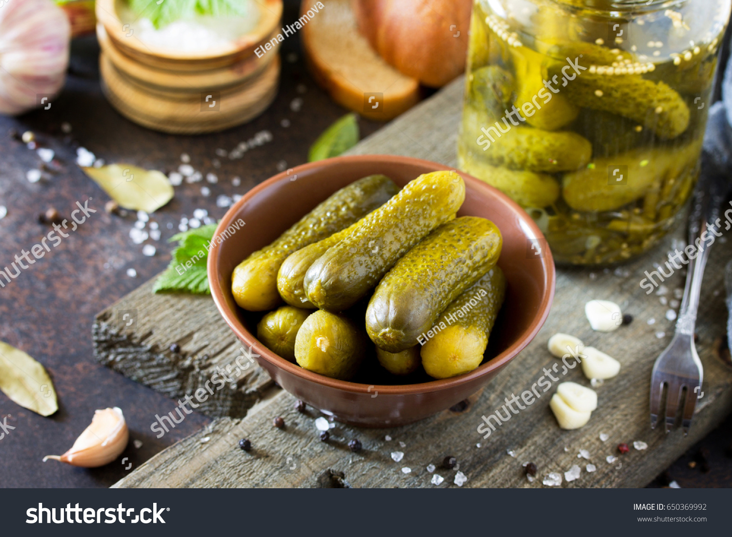 Marinated cucumbers gherkins. Pickles with mustard and garlic on a stone background. #650369992