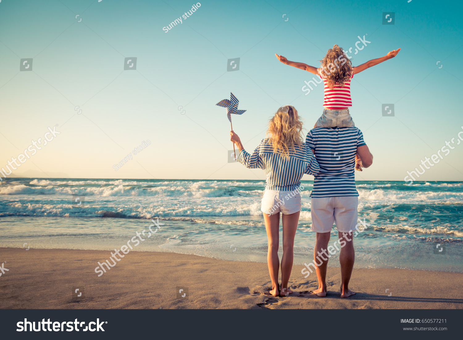 Happy family on the beach. People having fun on summer vacation. Father, mother and child against blue sea and sky background. Holiday travel concept #650577211