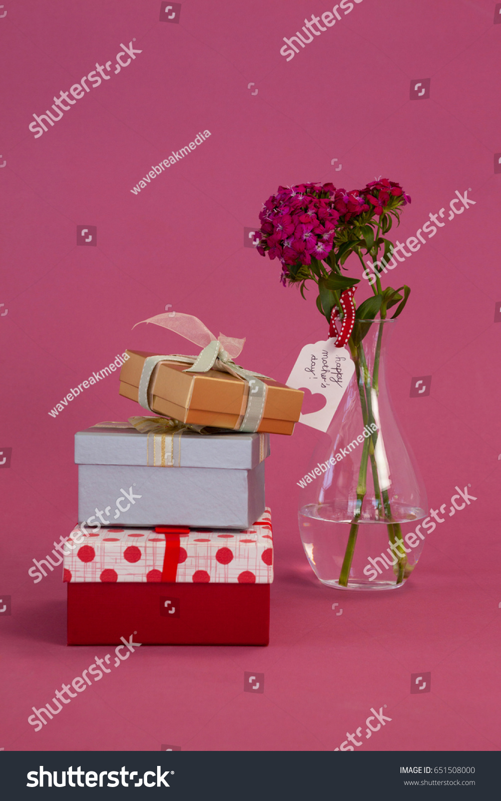 Stack of gift boxes and flowers vase on pink background #651508000