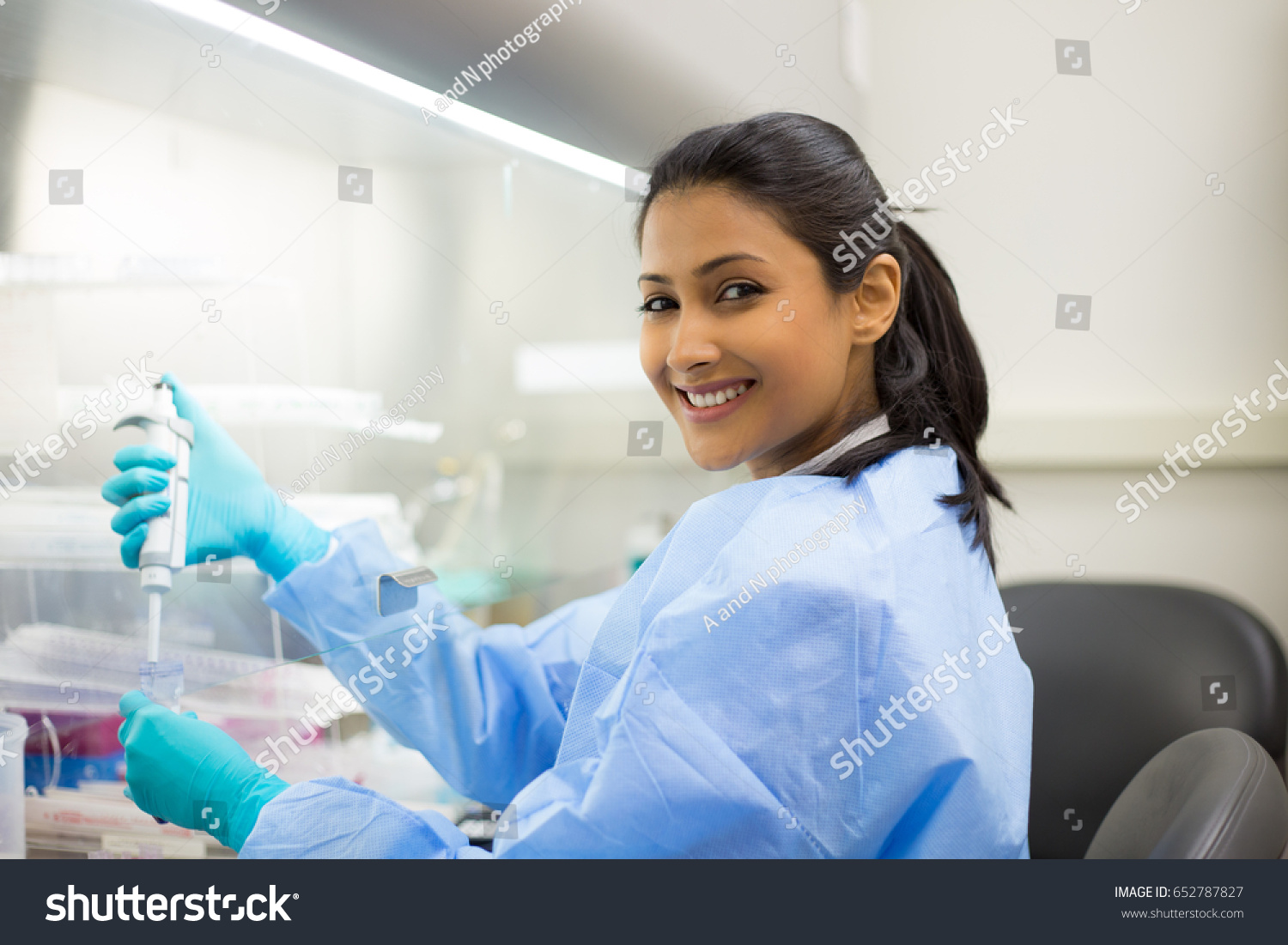 Closeup portrait, scientist pipetting from 50 mL conical tube with blue liquid solution, performing laboratory experiments, isolated lab . Forensics, genetics, microbiology, biochemistry #652787827