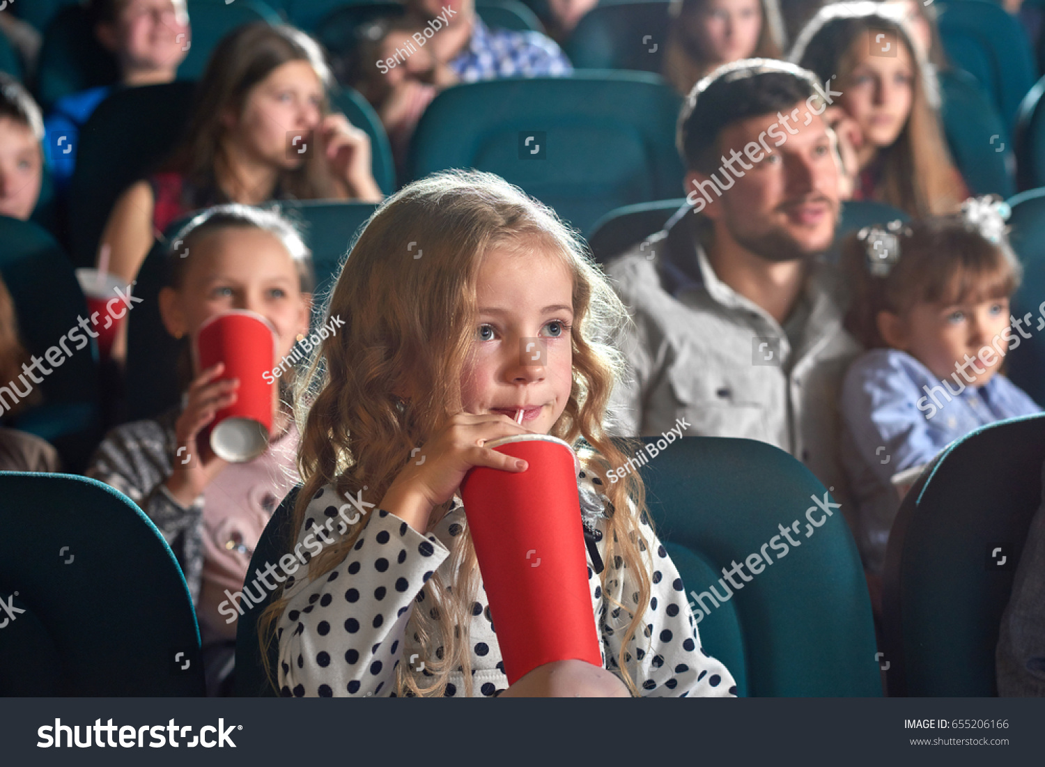Pretty little girl drinking coke sitting at the movie theatre enjoying watching cartoon copyspace happiness positivity people leisure children child kids kid cuteness innocence entertainment activity. #655206166