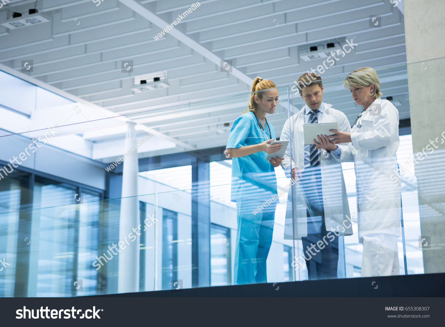 Medical team discussing over digital tablet in corridor at hospital #655308307