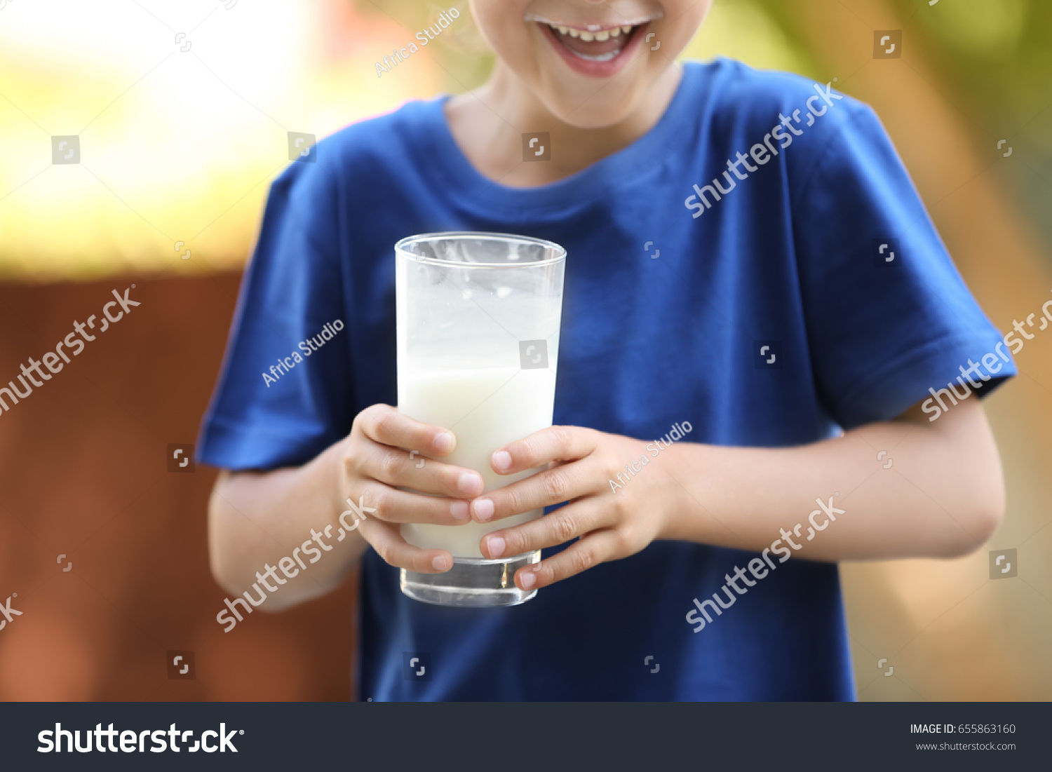 Small boy in blue shirt holding glass of milk, close up #655863160