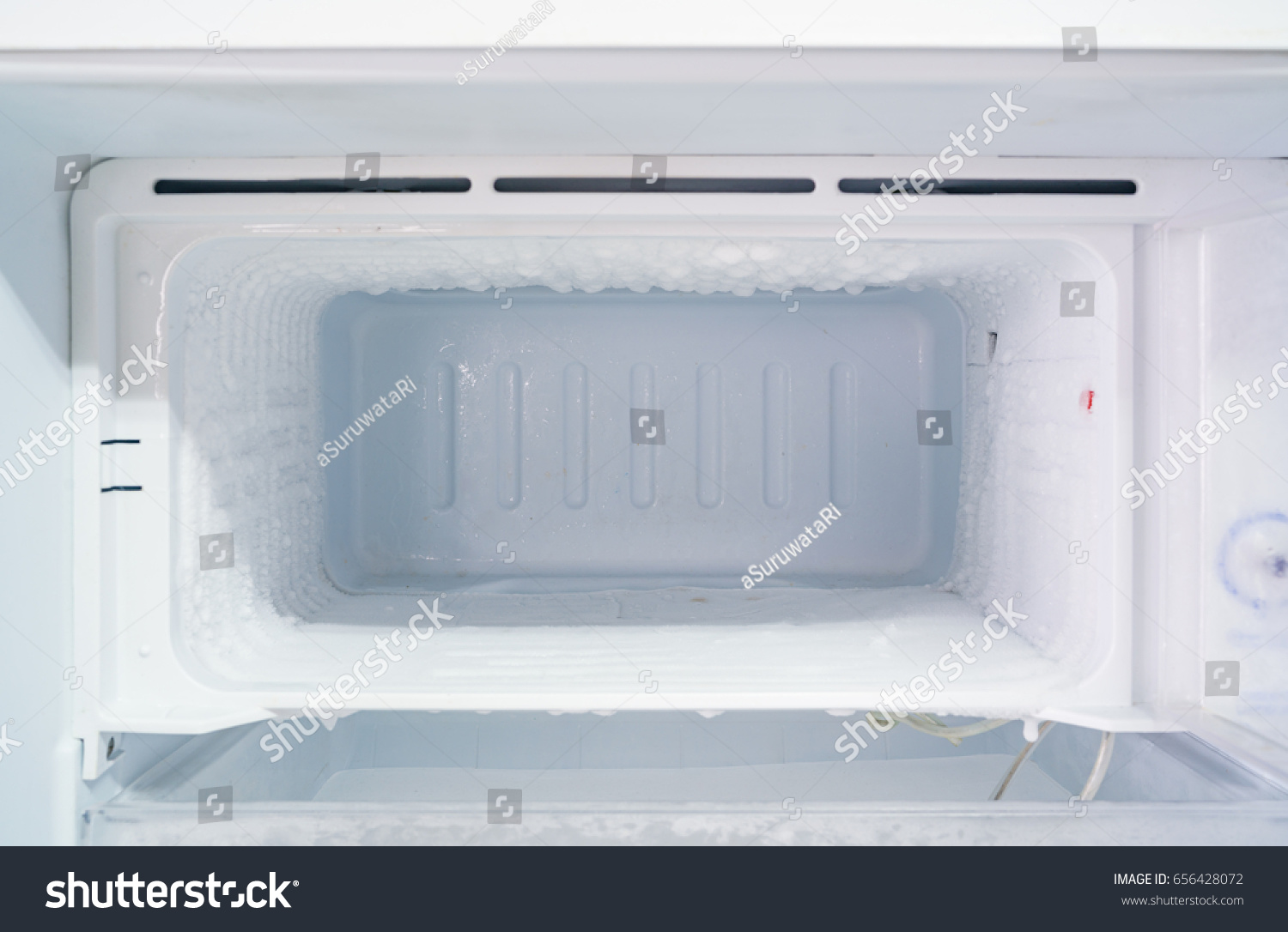 empty freezer of a refrigerator - Ice buildup on the inside of a freezer walls.  #656428072