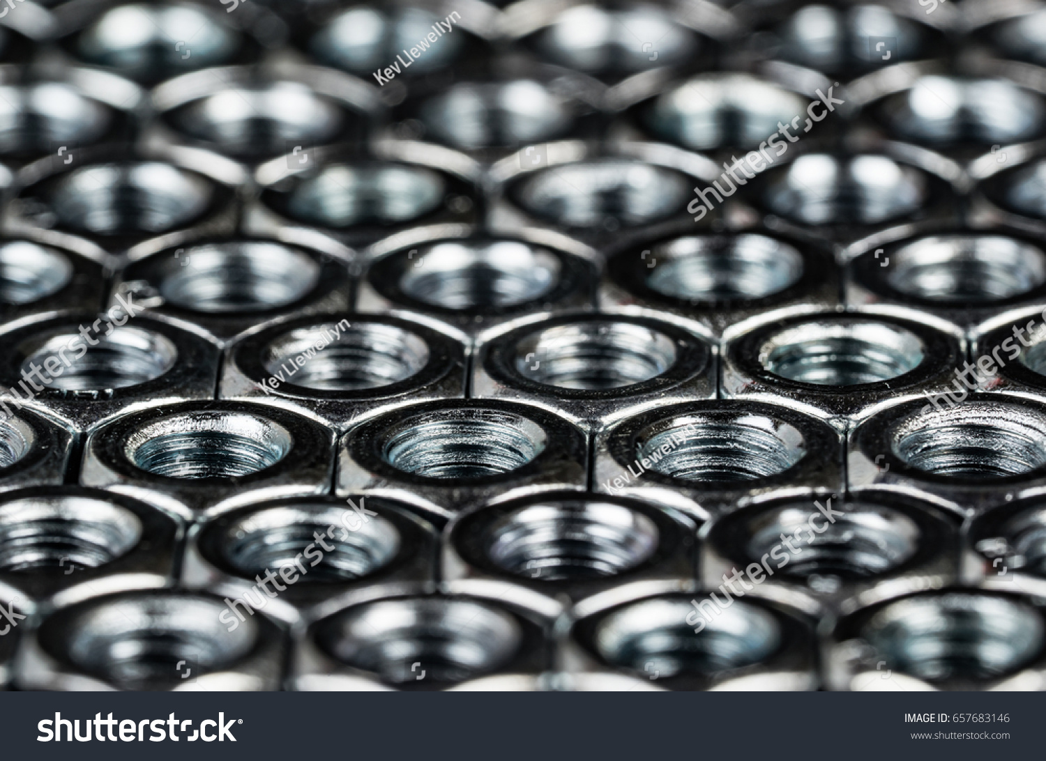 Nuts and bolts metal fasteners. Hexagon metal nuts arranges in a tessellation macro, with dramatic lighting to illustrate engineering or construction expertise. #657683146