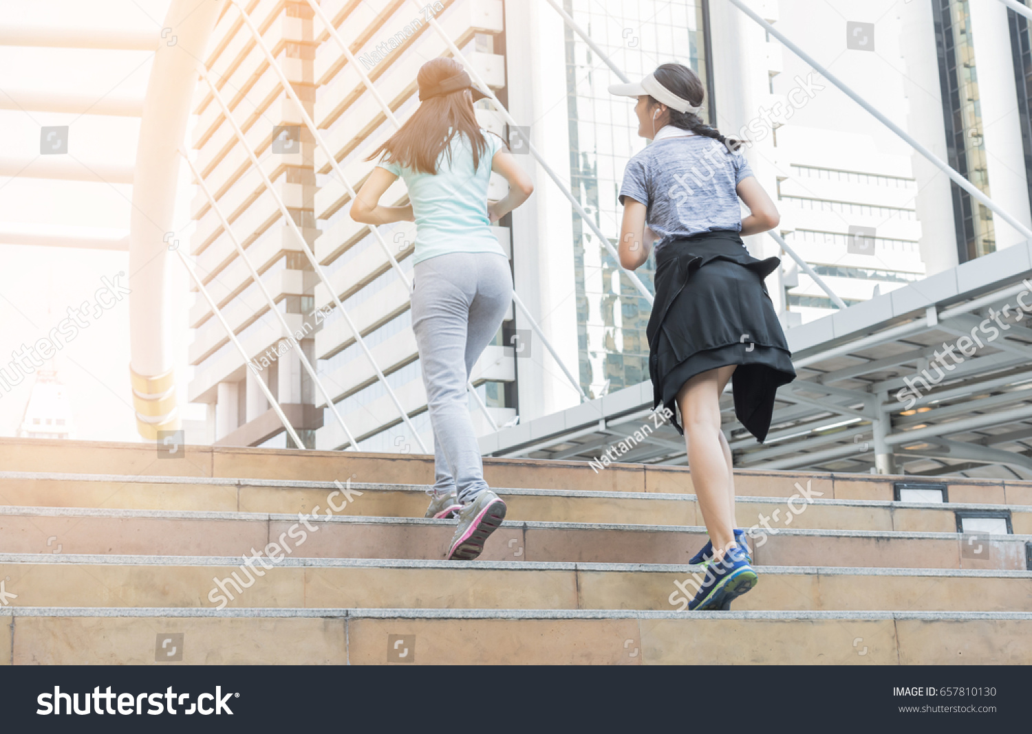 two sports woman running on stair with modern city, healthy lifestyle concept. #657810130