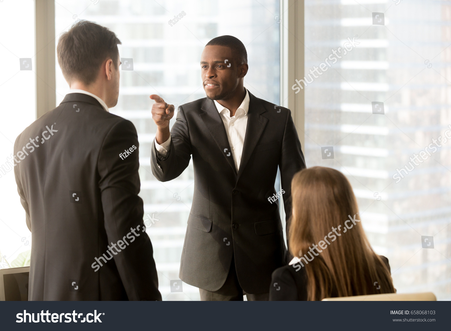 Angry african-american businessman threatens colleague, conflict between male workers at workplace, bullying and discrimination, black boss blames white employee responsible for failure, your fault #658068103