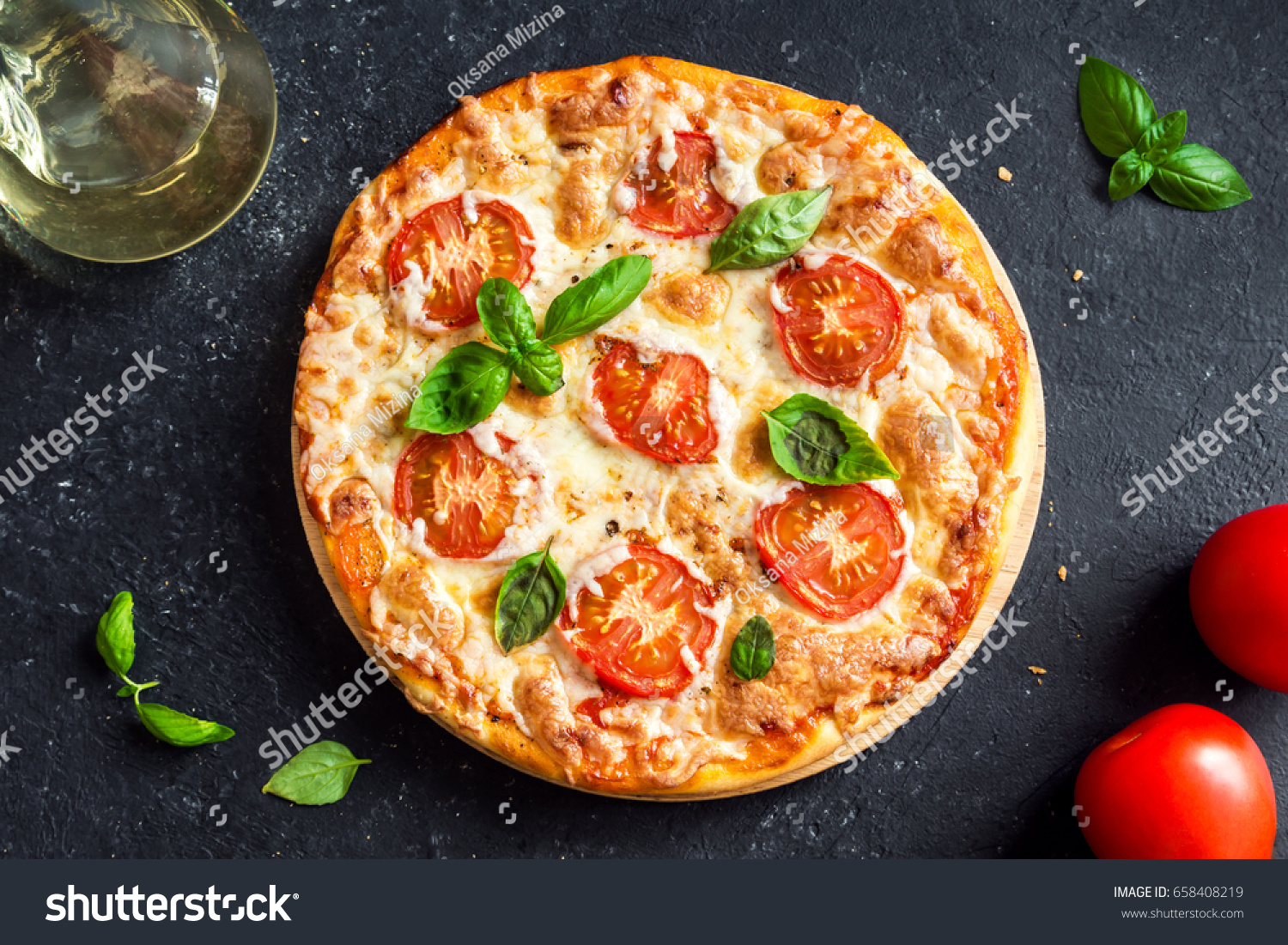 Pizza Margherita on black stone background. Homemade Pizza Margarita with Tomatoes, Basil and Mozzarella Cheese. #658408219