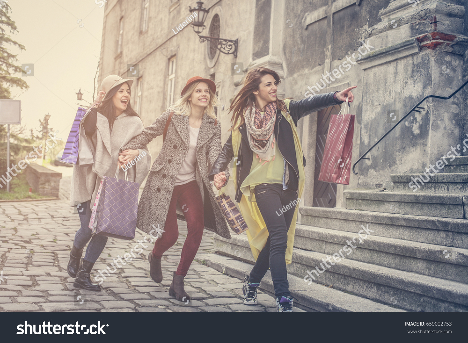Three best friends running on the street . Young female best friends doing shopping on the streets. #659002753