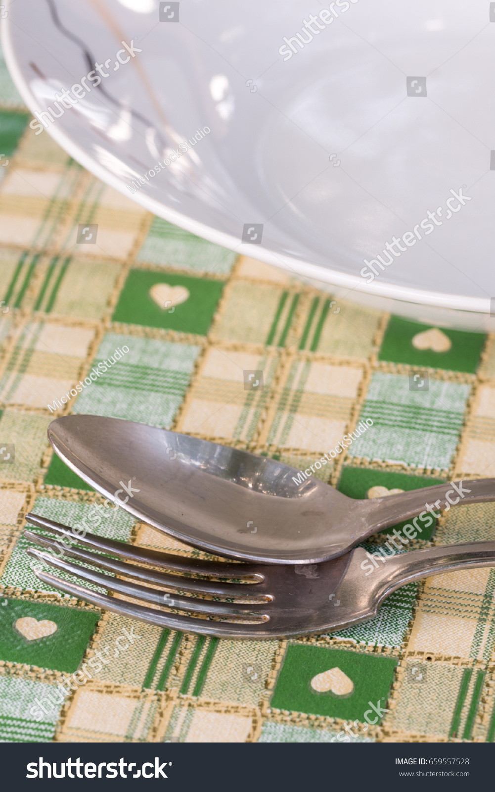 Metal spoon and fork beside plate on the served table. #659557528