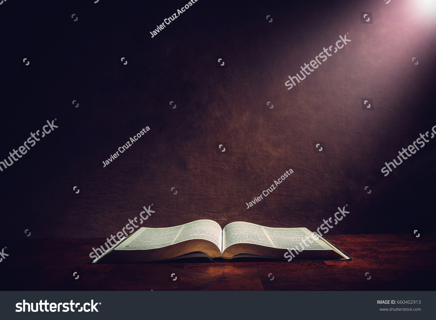 Light illuminating the Holy Bible on a wooded table. #660402913