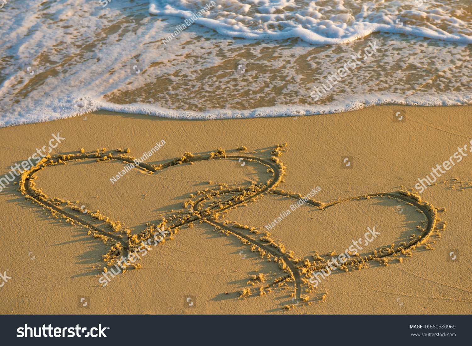 Two hearts together. Heart on a wet sand. Painted heart. Season of travel. Summer trips to the sea. Concept of leisure and travel. Waves wash away the painted heart on the sand
 #660580969