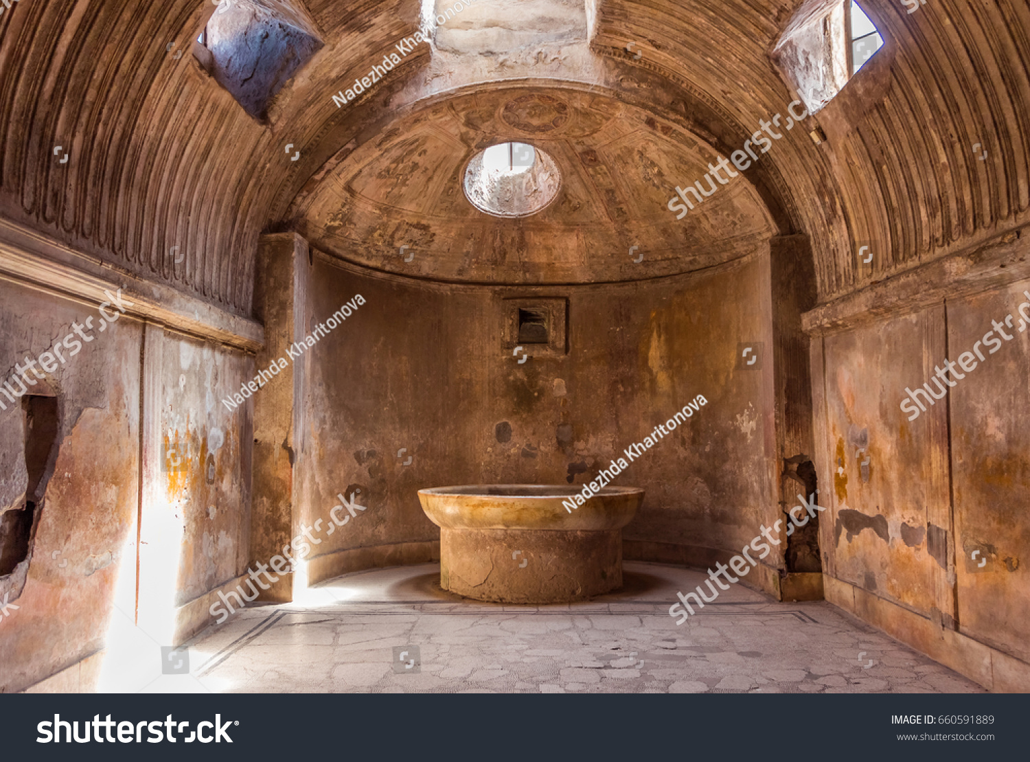 The interior of main public baths in ruins of Ancient Roman city Pompeii, Campania region, Italy. Sunny day. City destroyed by the eruption of Mount Vesuvius. Inside of Forum Baths. Big bowl for water #660591889