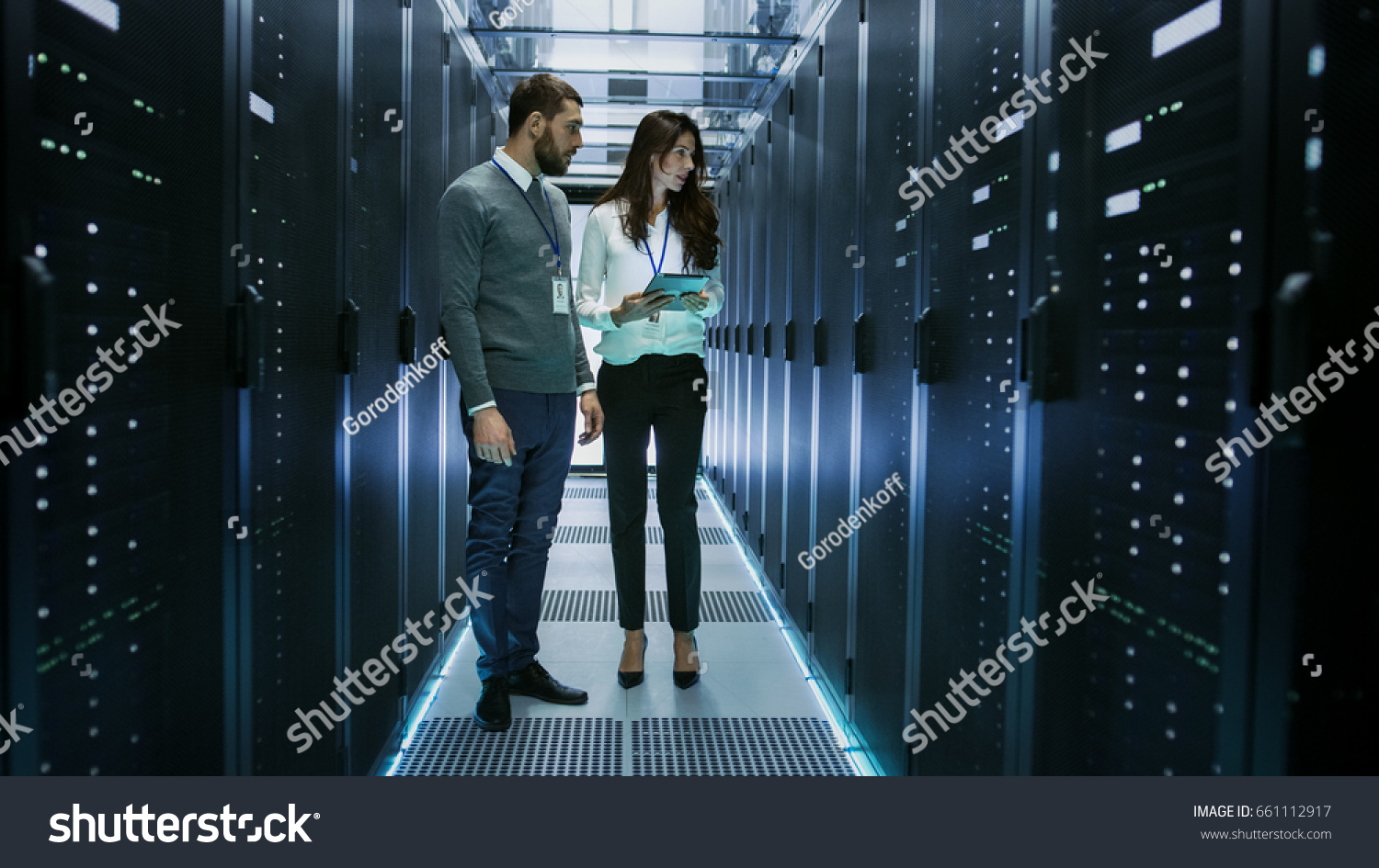 Female and Male IT Engineers Discussing Technical Details in a Working Data Center/ Server Room. #661112917