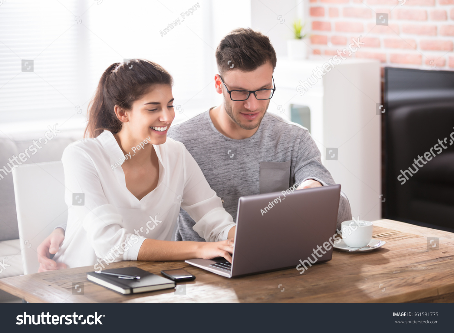 Smiling Young Couple Looking At Laptop On Table While Having Breakfast At Home #661581775