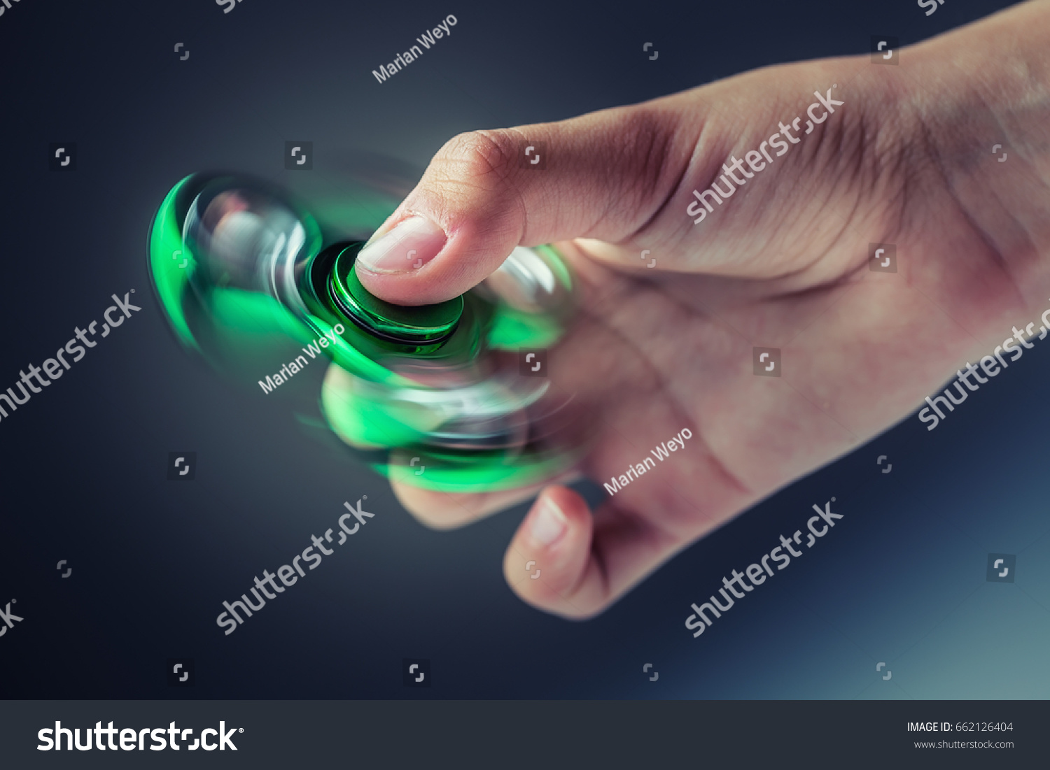 Green fidget spinner in a girl hand. #662126404