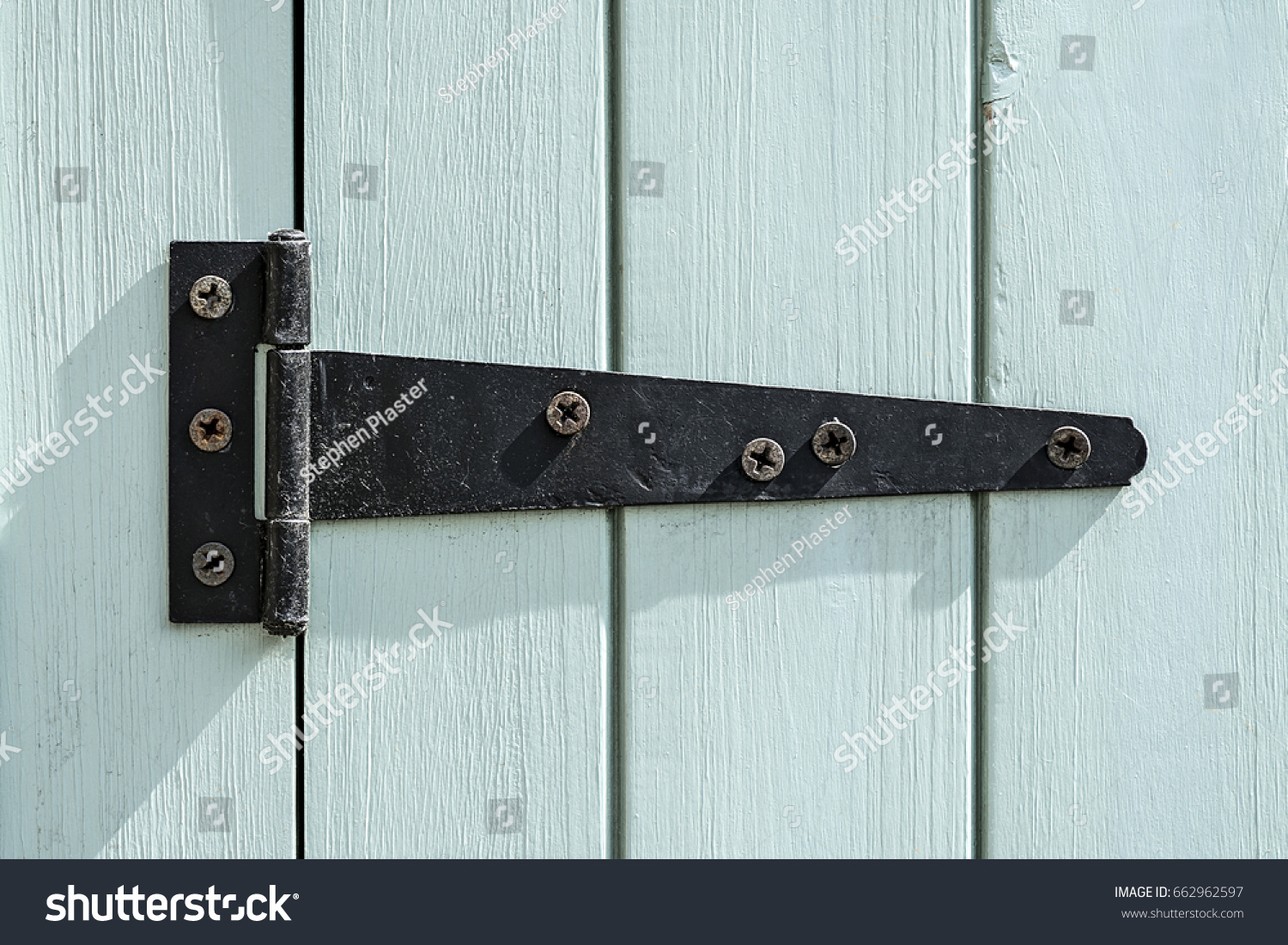 Black door hinge screwed to a bright painted wooden door. #662962597