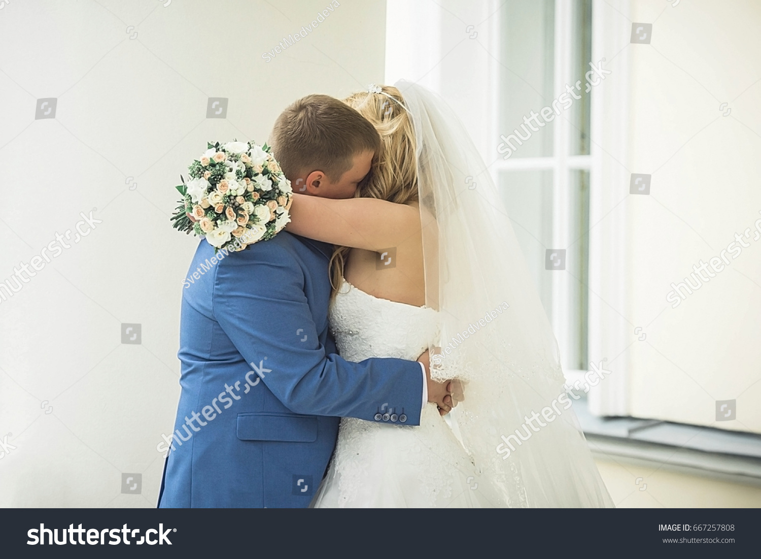 The groom embraces the bride? The groom hugs bride from behind. Woman and man in wedding dress outdoors holding hands. A young man gently embraces his bride in a wedding dress. Wife and husband. #667257808