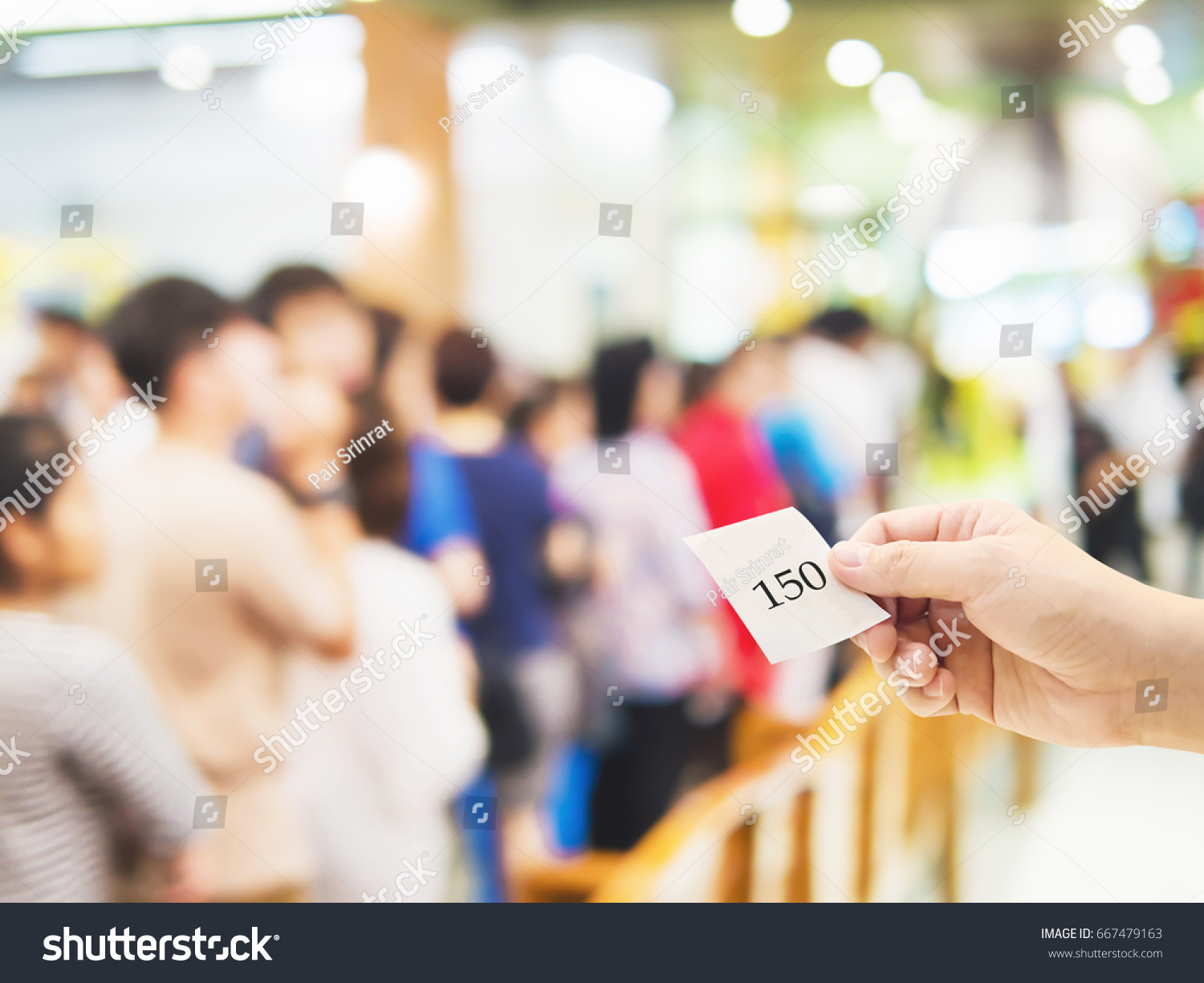Male hand holding queue card over long line waiting people #667479163