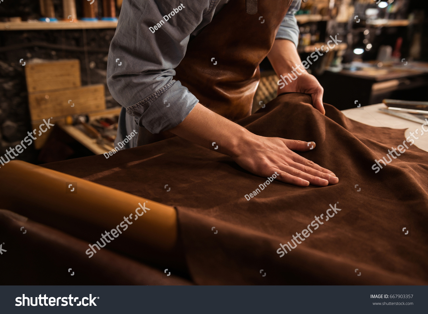 Close up of a male shoemaker working with leather textile at his workshop #667903357
