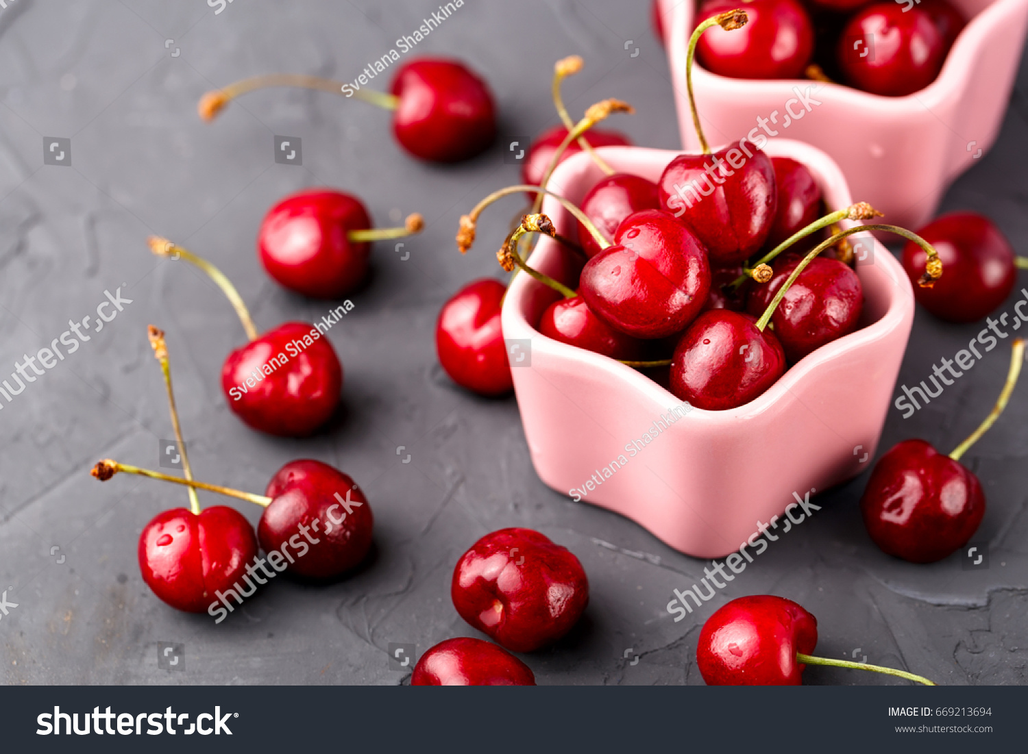 Ripe, juicy cherry in two ceramic pink bowls on the table #669213694