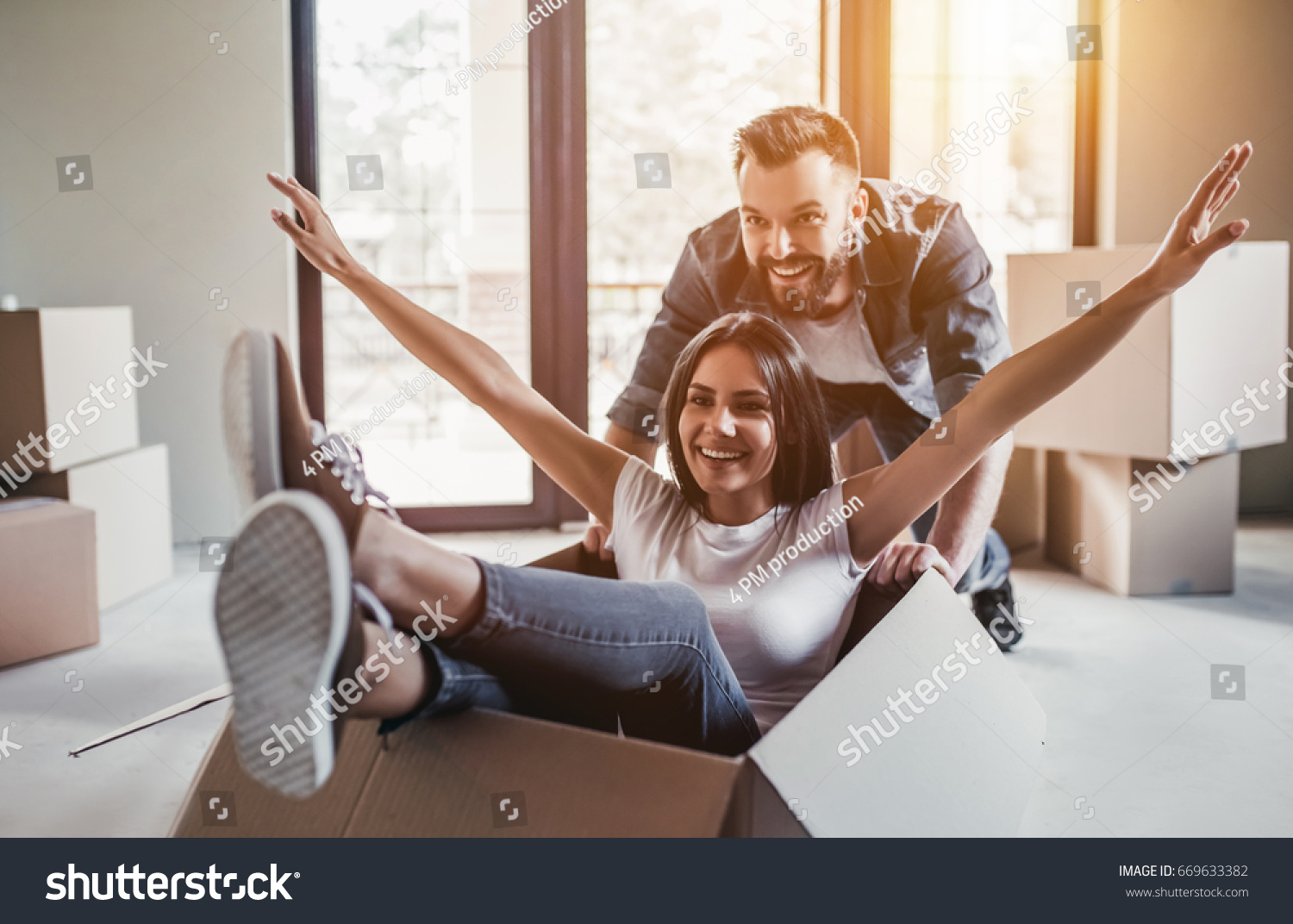 Happy couple is having fun with cardboard boxes in new house at moving day. #669633382