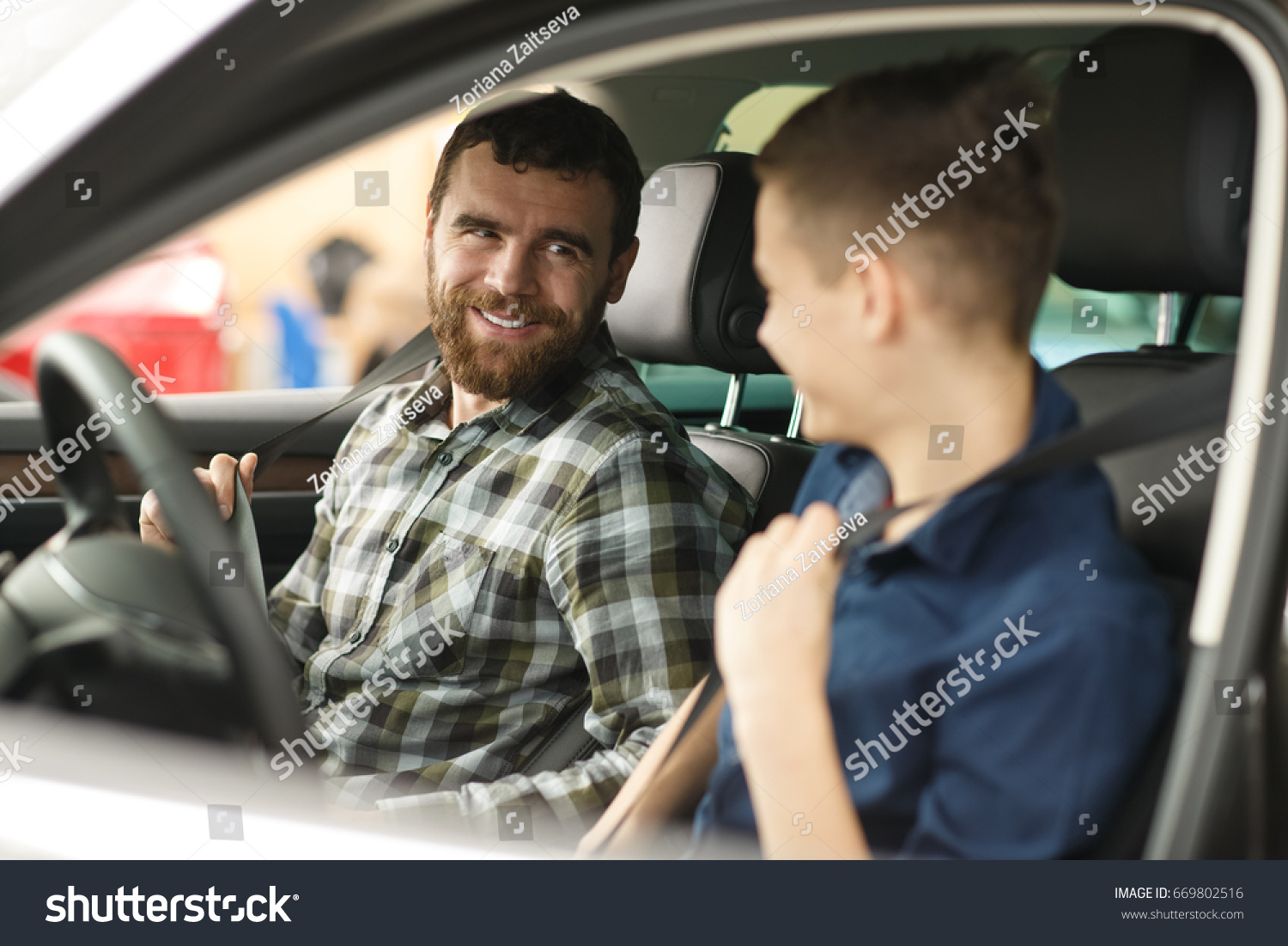 Shot of a young boy talking to his cheerful father sitting together in a new car driving travelling trip journey happiness lifestyle parent vehicle automobile rent safety insurance family parenting  #669802516
