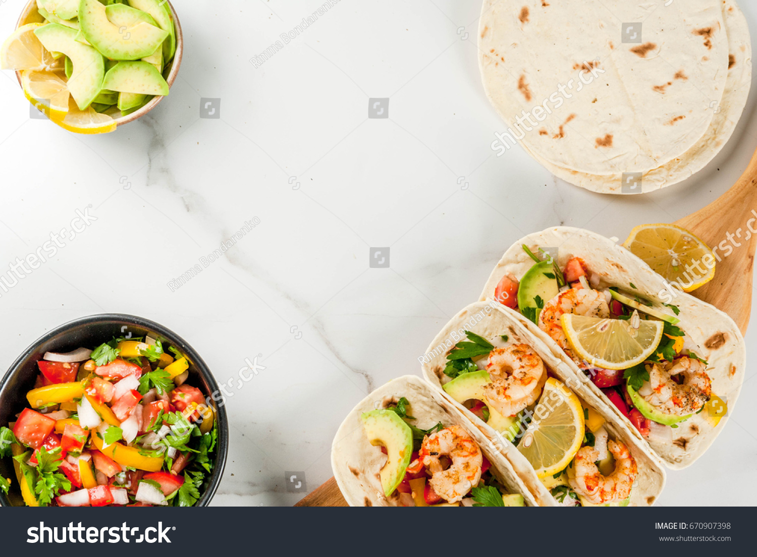 Seafood. Mexican food. Tortilla tacos with traditional homemade salsa salad, parsley, fresh lemon, avocado and grilled shrimp pawns. On a white marble background. Top view copy space #670907398