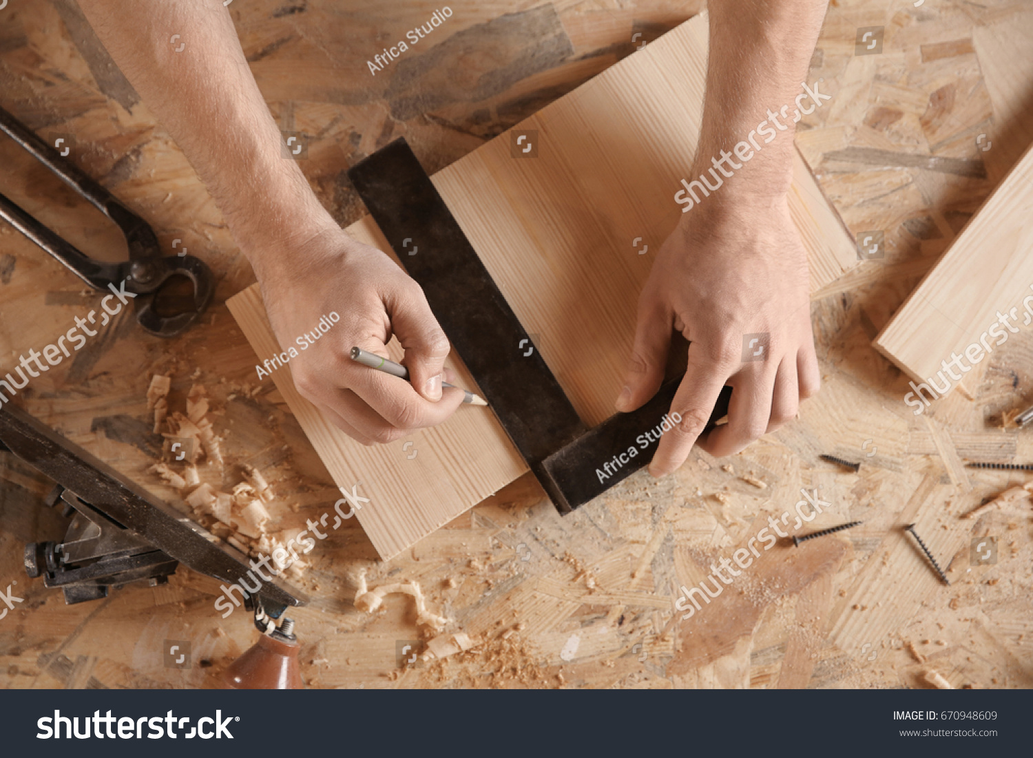 Carpenter marking wooden board in workshop #670948609