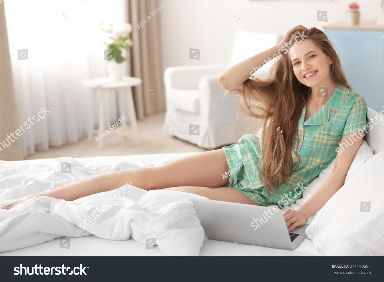 Morning of beautiful young woman sitting on bed with laptop #671140897