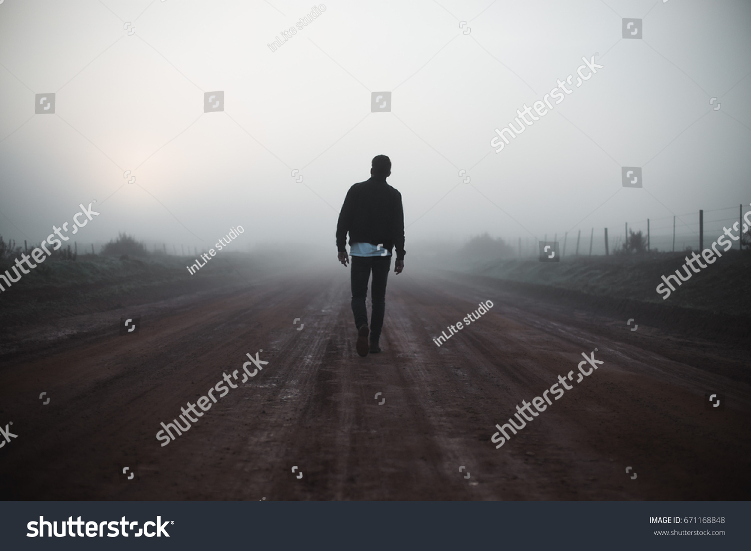 Man walking away on misty road #671168848